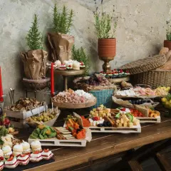 Bogaty stół z przekąskami: sery, owoce, ciastka, pieczywo. Zastanawiasz się, ile kosztuje catering na 20 osób? To bogactwo smaków!