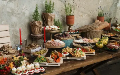 Bogaty stół z przekąskami: sery, owoce, ciastka, pieczywo. Zastanawiasz się, ile kosztuje catering na 20 osób? To bogactwo smaków!